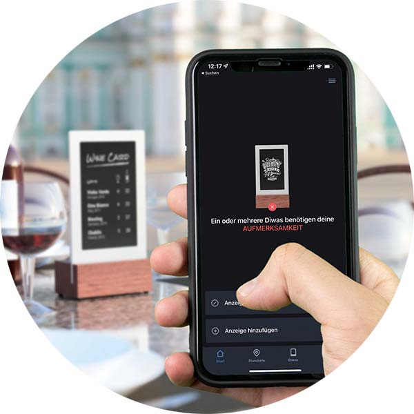 Smartphone mit der Diwa App sendet eine Anzeige an einen digitalen Tischaufsteller.